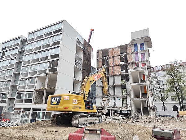 Zur Hälfte abgerissenes Haus, davor gelber Abrissbagger