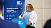 Claudia Meijering, Rede anlässlich der Wiedereröffnung der Hans-Scholl-Halle Auf dem Foto sieht man Claudia Meijering, wie sie an einem Rednerpult steht und ihre Rede hält. Dahinter ein Banner mit der Aufschrift "Studierendenwerk München Oberbayern".
