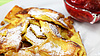 Eine Portion Kaiserschmarrn mit Puderzucker. Rechts oben im Anschnitt ein Schälchen roter Marmelade.