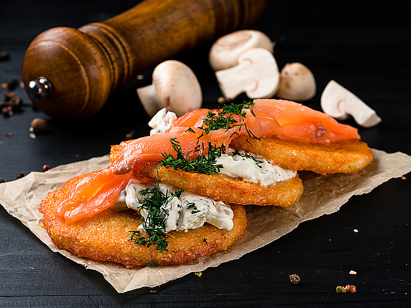 Das Bild zeigt einen Reibekuchen mit Lachs und einem Dip. 