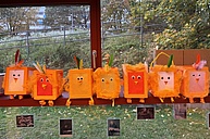 Orangefarbene Laternen, die wie Tiere aussehen, da sie mit Ohren, Augen und Füßen beklebt worden sind, stehen alle in einer Reihe