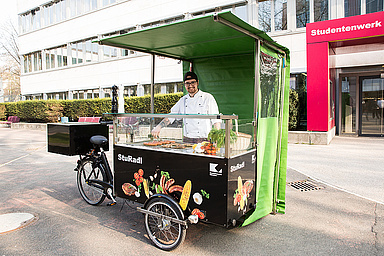 Ein Koch steht am Grillfahrrad