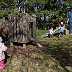 Graten mit Rutsche, Spielholzhaus, Kindern und Erzieherin