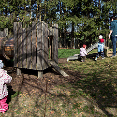 Graten mit Rutsche, Spielholzhaus, Kindern und Erzieherin 