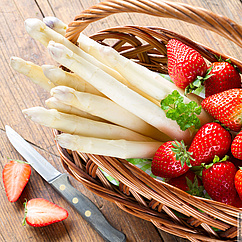 Auf dem Bild ist ein Korb gefüllt mit Erbeeren und weißem Spargel zu sehen.