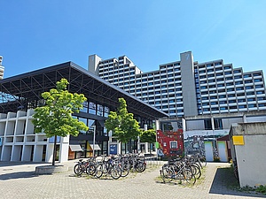 Treppenförmig angeordnetes Hochhaus, davor Flachbau