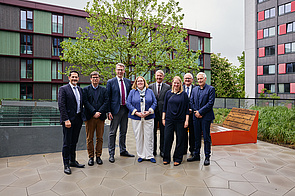 Gruppenfoto mit 8 Personen auf der Terrasse des Wohnheims, im Hintergrund das Wohnheimgebäude
