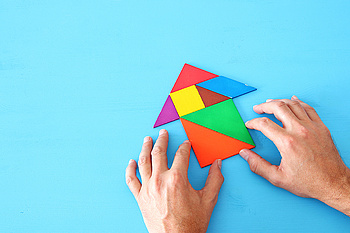 rocket made from tangram puzzle on blue pastel wooden background.